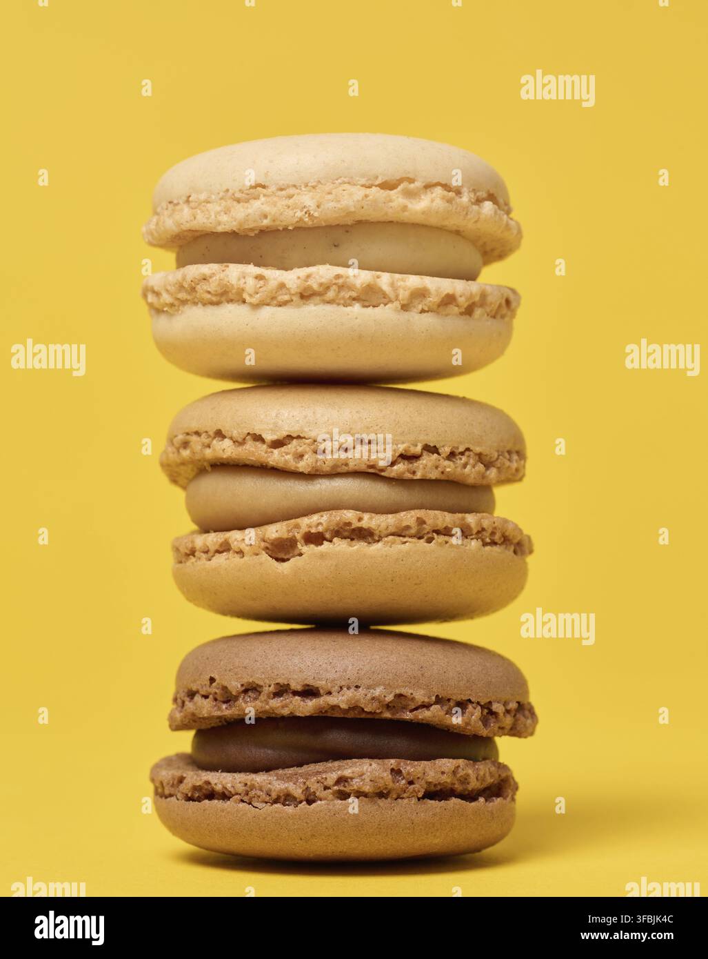 Pila di macaron di cioccolato su sfondo giallo Foto Stock