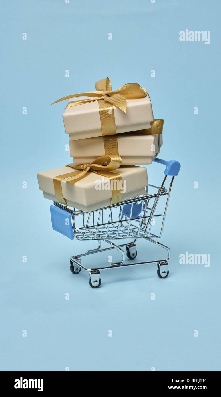 Carrello della spesa in miniatura con una pila di scatole regalo, imballaggio beige Foto Stock