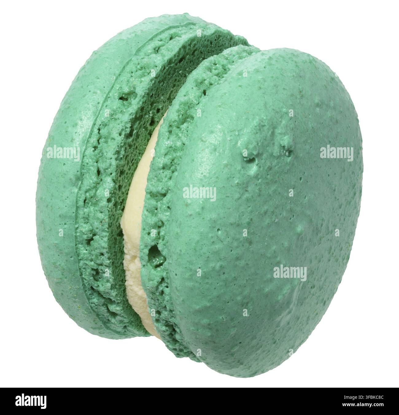 Macaron verde menta con ripieno bianco cremoso, sfondo isolato. Il macaron ha un guscio liscio e poroso Foto Stock