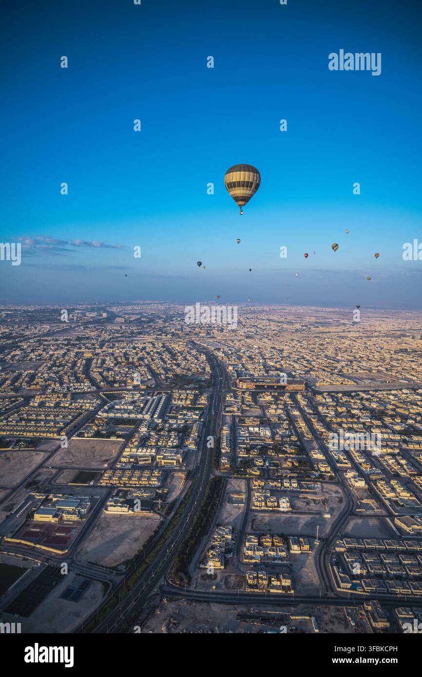 Mongolfiere volano su una città estesa all'alba Foto Stock