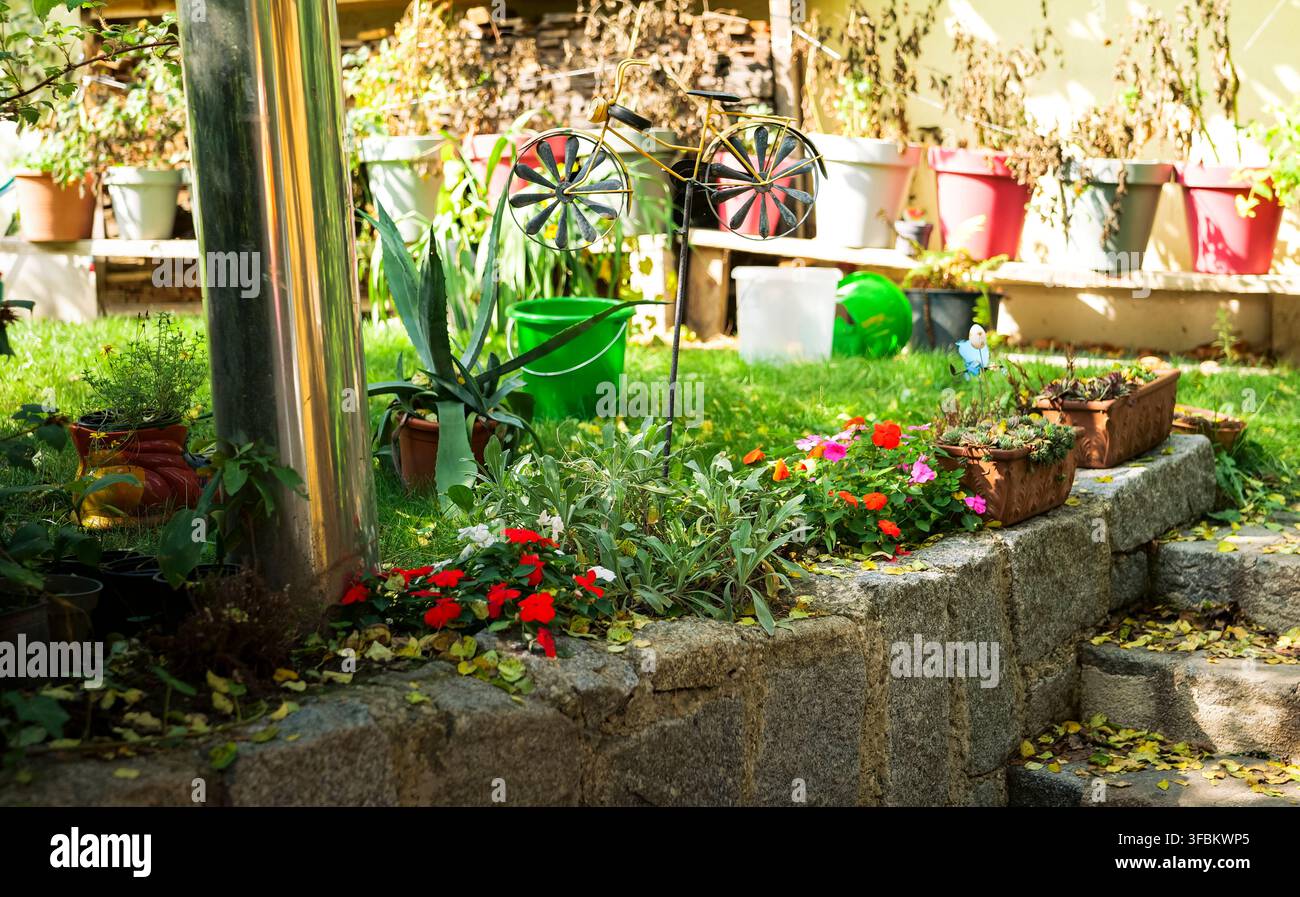 Giardino austriaco rustico con piante in vaso e un muro di pietra che evidenzia il fascino rustico con dettagli naturali e artigianali. Foto Stock