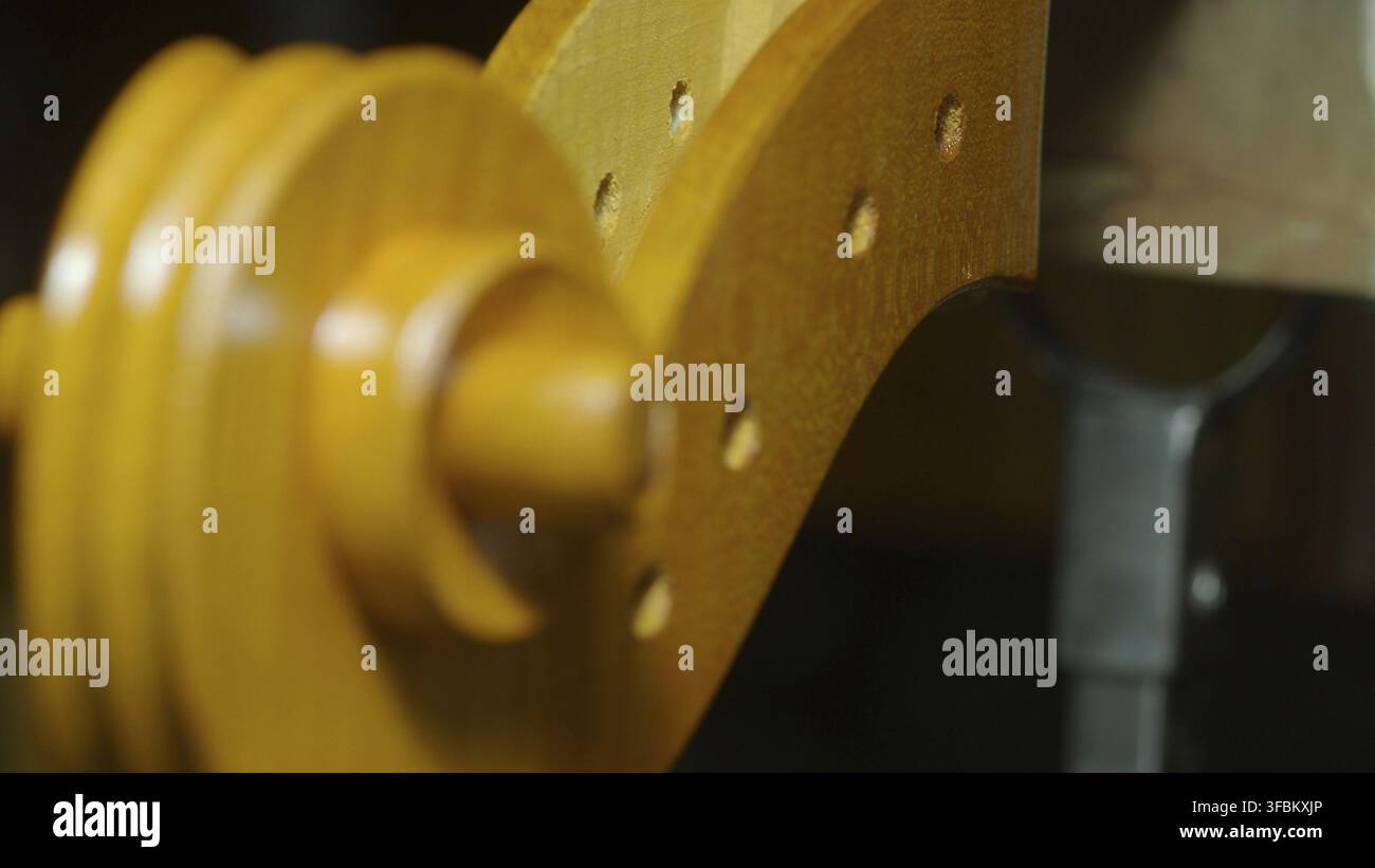 Luthier lavora meticolosamente sul rotolo e sul collo di un violoncello nella loro bottega, utilizzando strumenti e tecniche specializzati per modellare e assemblare il del Foto Stock