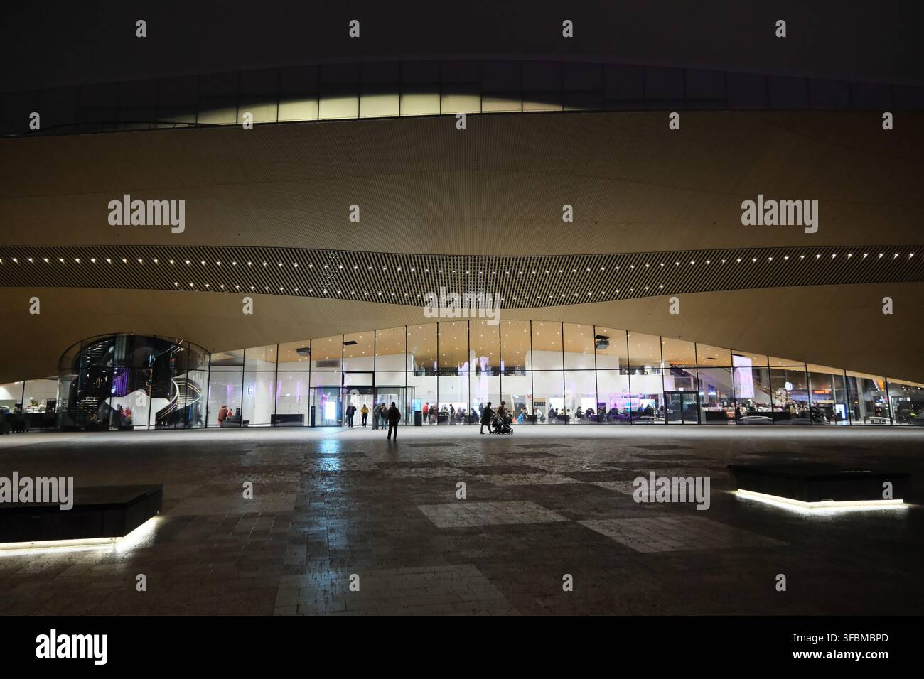 Helsinki, Finlandia-30 nov. 2025: Biblioteca centrale Oodi a Helsinki. Vista frontale notturna della facciata curva in legno e dell'ingresso illuminato Foto Stock