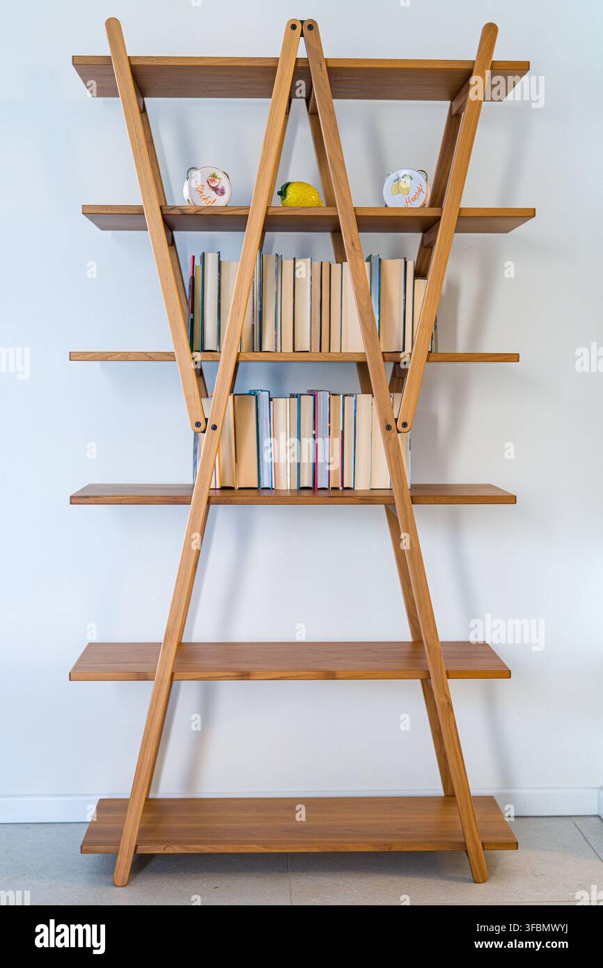 Scaffale a scala di legno con libri in un interno minimalista Foto Stock