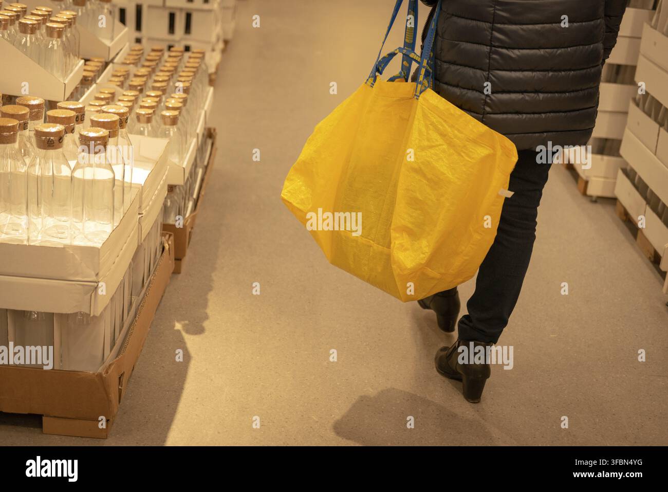 Acquirente con borsa della spesa gialla di marca nel negozio Ikea. Esperienza di acquisto presso Ikea Foto Stock