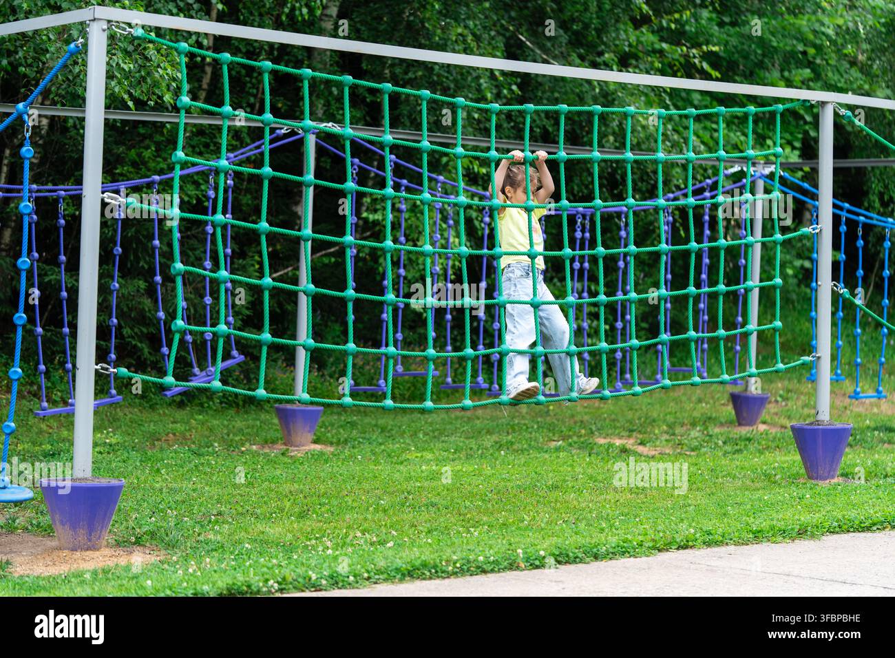 Ragazza che sale sulla rete di corda del parco giochi all'aperto Avventura. Foto Stock