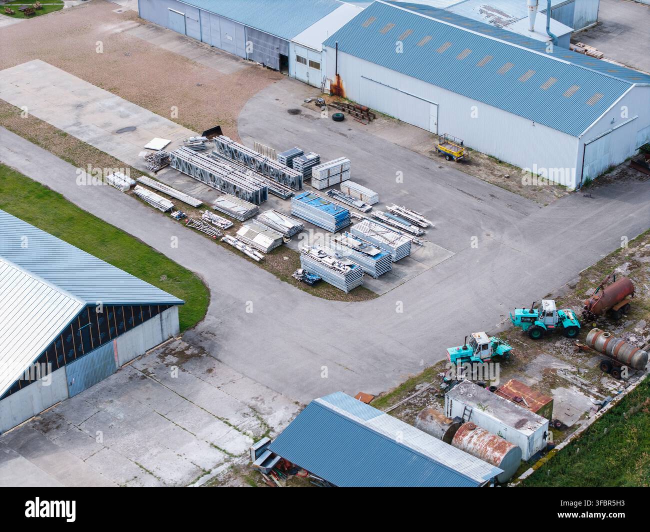 Vista aerea di trattori della serie K-700 parcheggiati vicino a magazzini industriali e aree di stoccaggio in Lettonia. Foto Stock