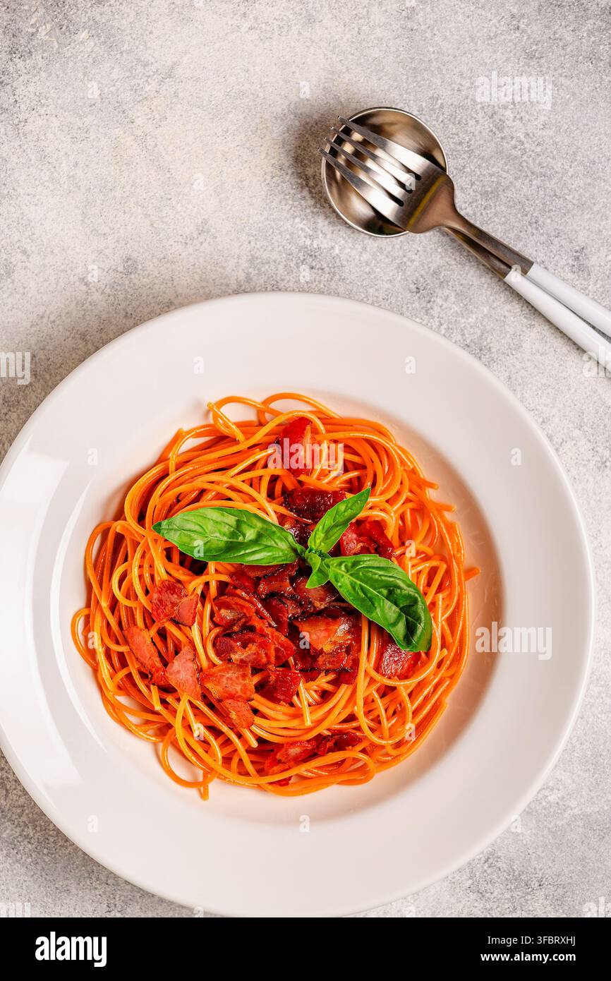 Pasta senza glutine, spaghetti di lenticchie con salsa. Pasta con salsa di carne guarnita con foglie di basilico. Foto Stock
