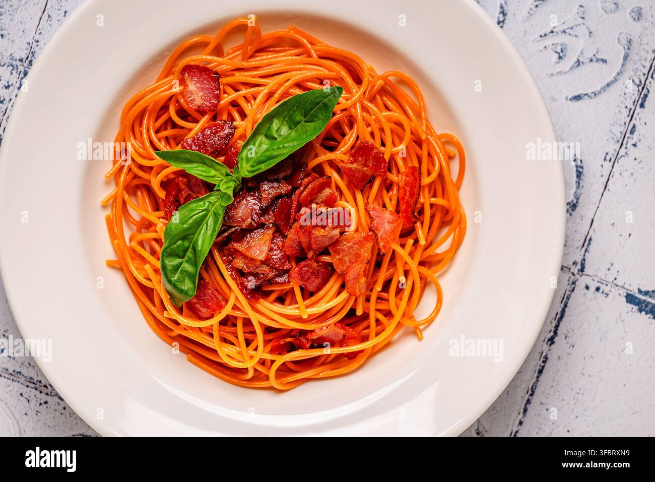 Pasta senza glutine, spaghetti di lenticchie con salsa. Pasta con salsa di carne guarnita con foglie di basilico. Foto Stock