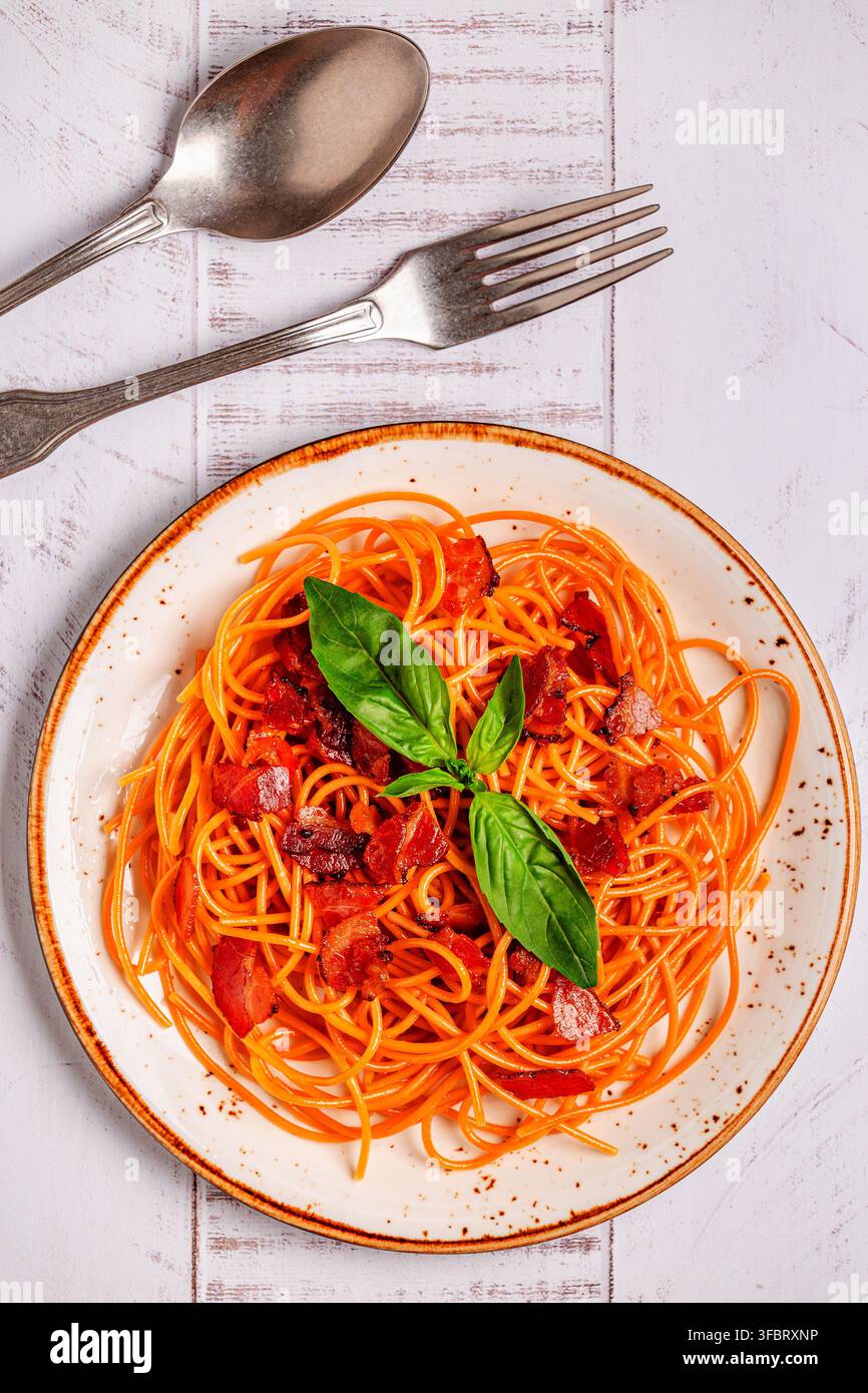 Pasta senza glutine, spaghetti di lenticchie con salsa. Pasta con salsa di carne guarnita con foglie di basilico. Foto Stock