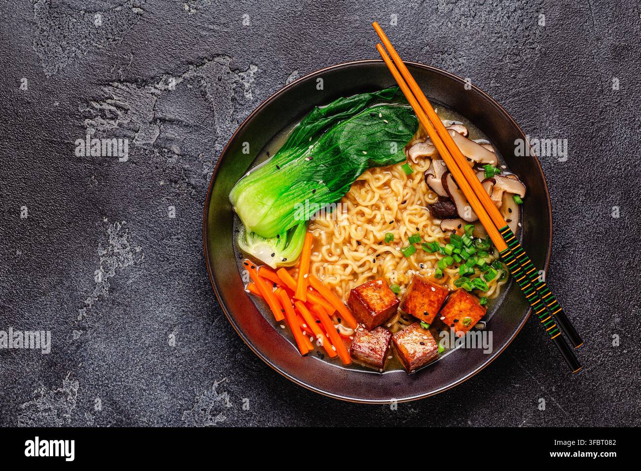 Zuppa miso ramen con noodles servita con tofu, bok choy, carote e funghi in una ciotola. Foto Stock
