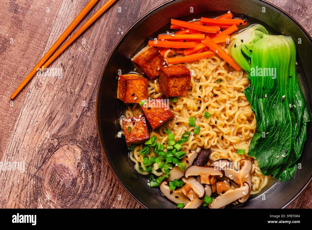Zuppa miso ramen con noodles servita con tofu, bok choy, carote e funghi in una ciotola. Foto Stock