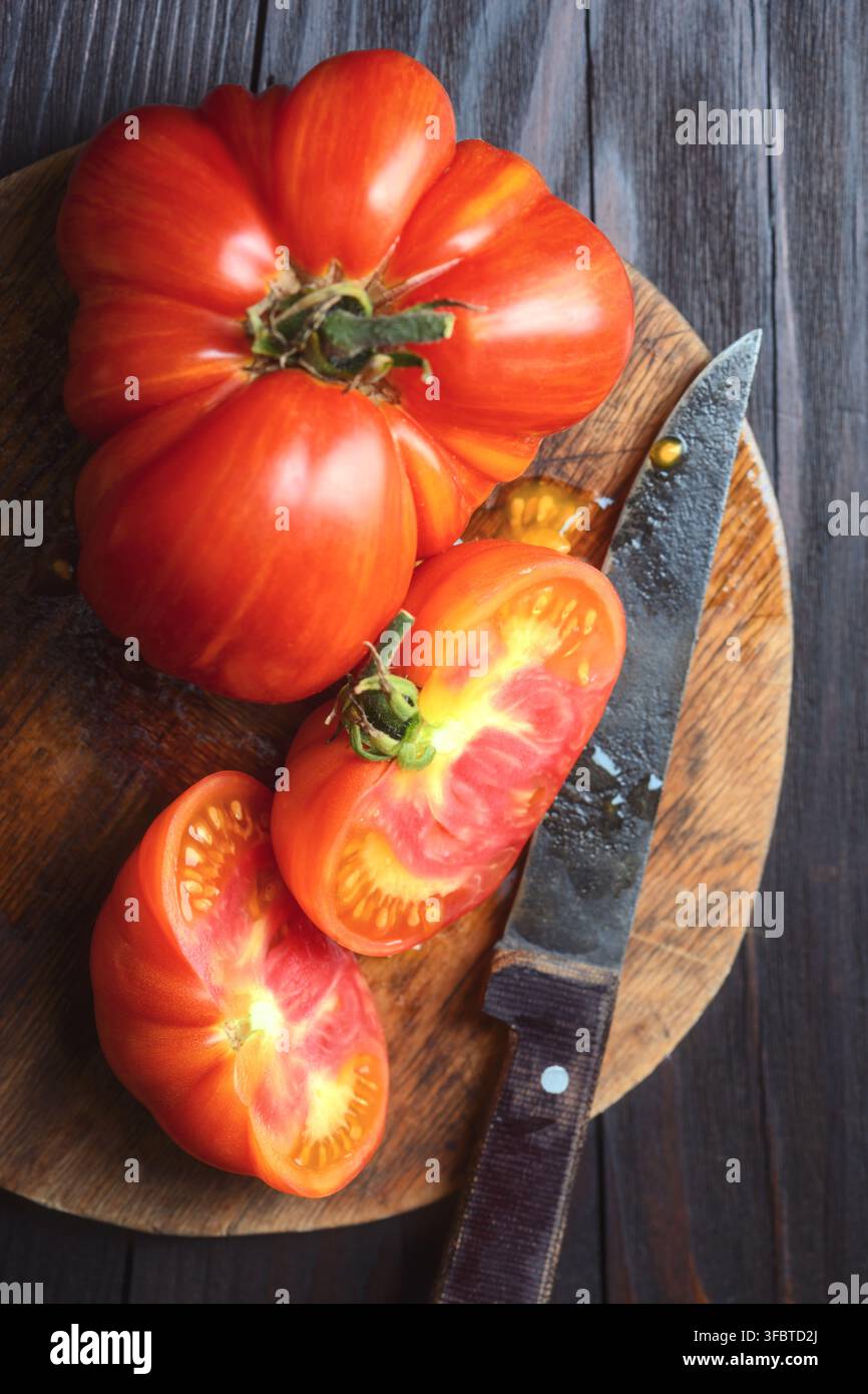 Pomi d’api antichi interi e affettati su tavola di legno con coltello. Scena di cucina rustica, prodotti biologici della fattoria Foto Stock
