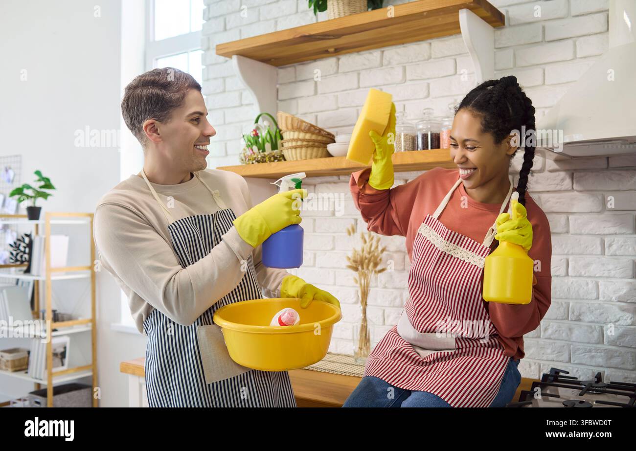 Coppia felice che pulisce la cucina insieme, lavoro di squadra divertente e igiene domestica Foto Stock
