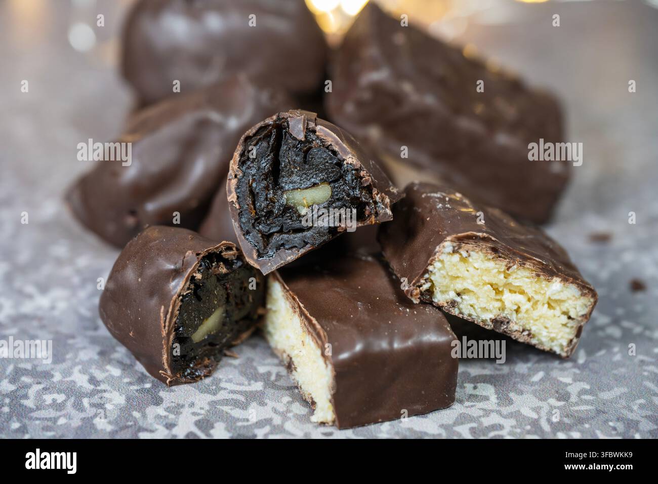 Un primo piano di una varietà di caramelle ricoperte di cioccolato fatte in casa, alcune tagliate per rivelare ripieni di frutta secca con una noce e cocco Foto Stock