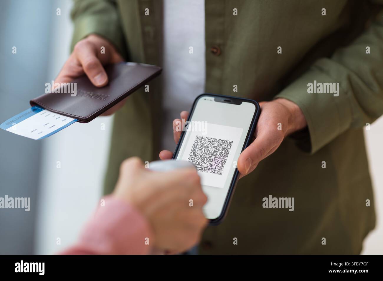 Persona irriconoscibile che scansiona un codice QR con uno smartphone e tiene il passaporto al check-in dell'aeroporto Foto Stock