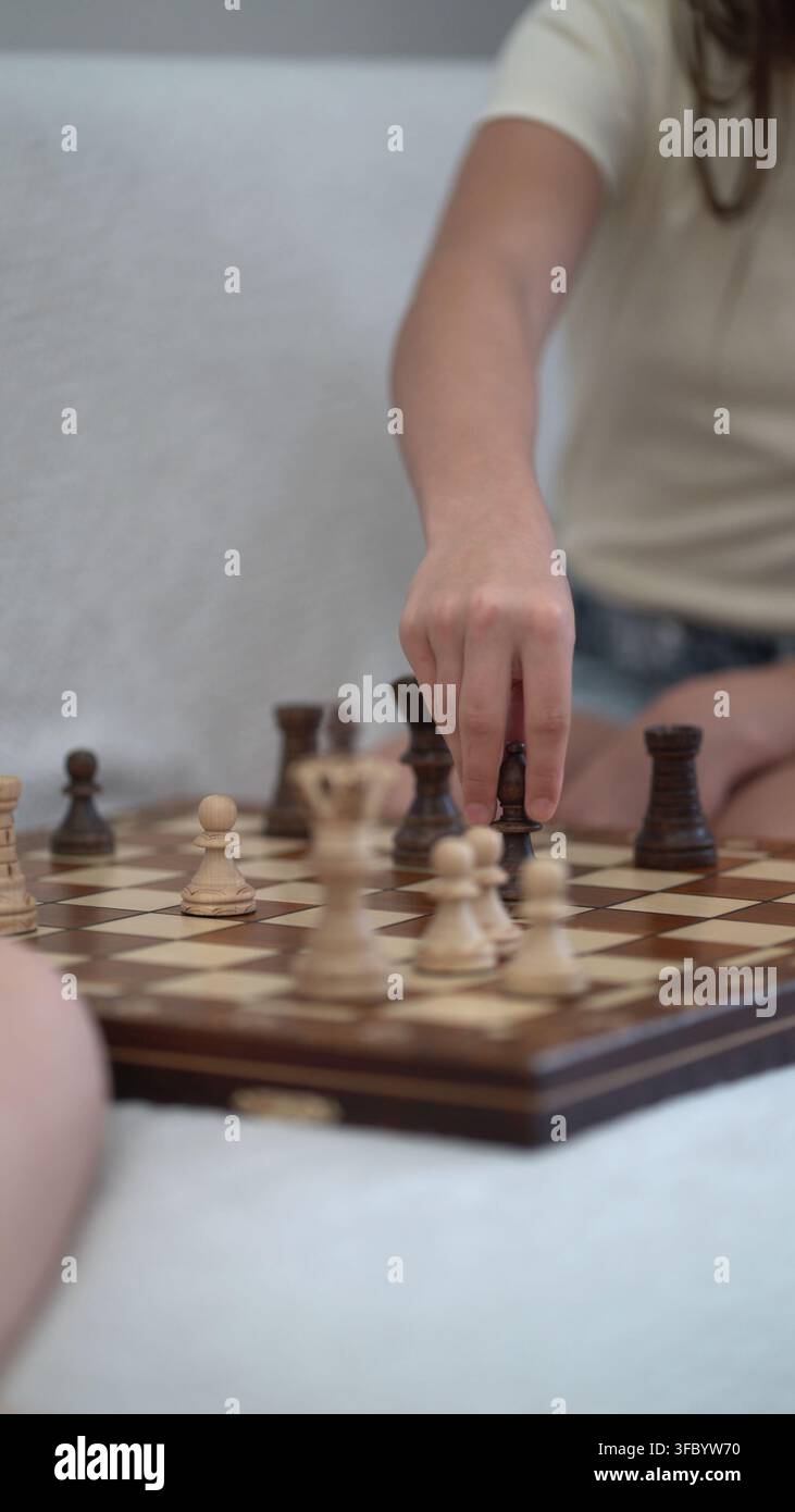 I fratelli si godono una partita di scacchi riflessiva al chiuso, fratello e sorella fanno mosse attente con pedine classiche mentre condividono un felice tempo libero dell'infanzia Foto Stock