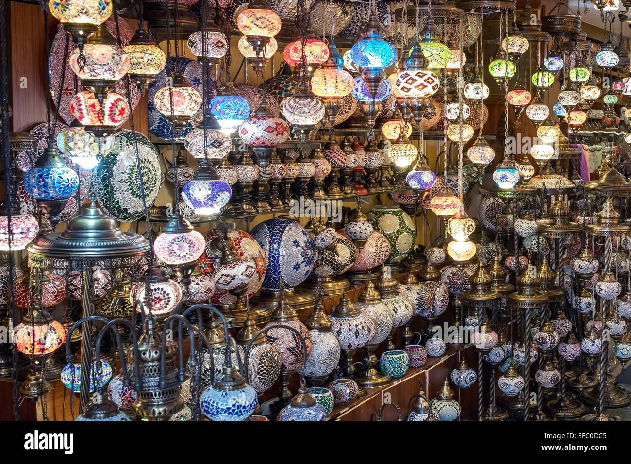 File di lampade in vetro a mosaico colorate pendono dense in un negozio tradizionale turco, illuminate da un caldo bagliore Foto Stock