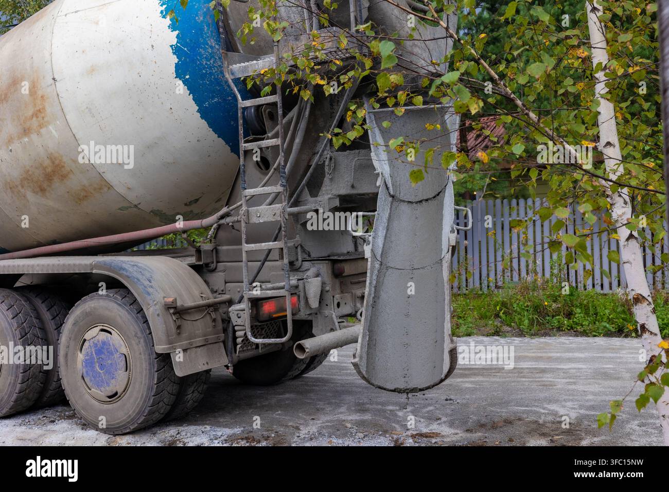 Camion betoniera pesante con chut in acciaio pulito in piedi su un cantiere stradale all'aperto. Concetto: lavori di costruzione generali Foto Stock