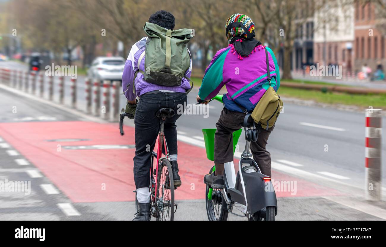 Due ciclisti sulla pista ciclabile urbana. Contenuto sui pendolari urbani e il ciclismo. Foto Stock