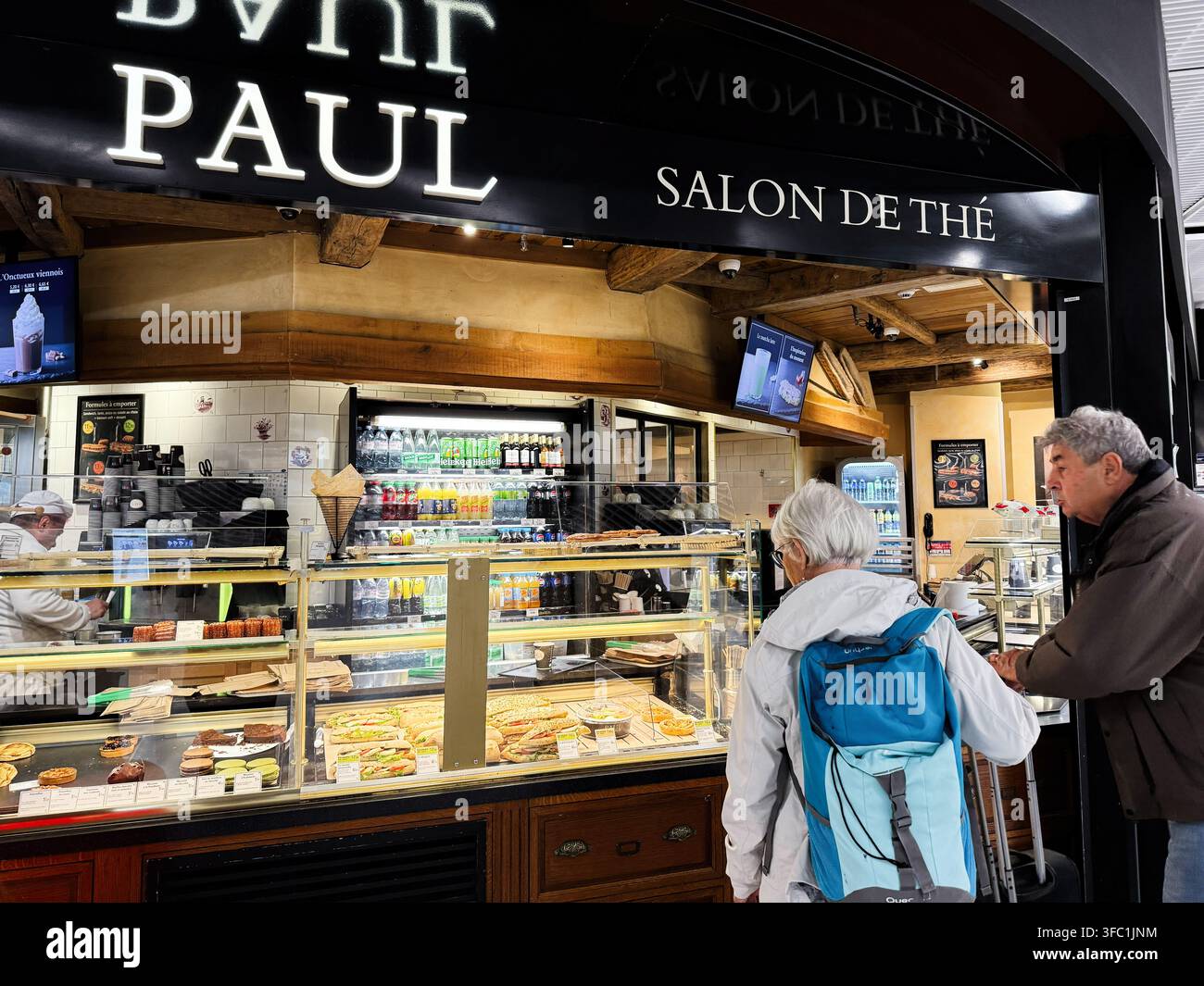 Parigi, Francia - 14 maggio 2026: Viaggiatori anziani ordinano caffè e pasticcini a un bancone affollato del salone da tè Paul a Parigi, in Francia. Foto Stock