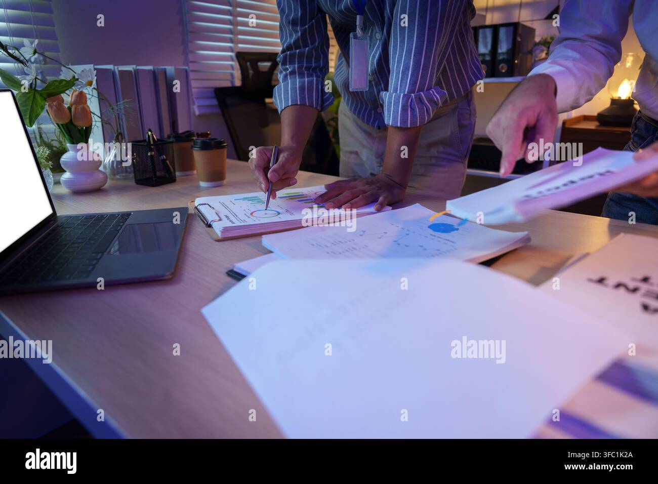 Team aziendale che analizza grafici finanziari in una riunione d'ufficio per la pianificazione strategica Foto Stock