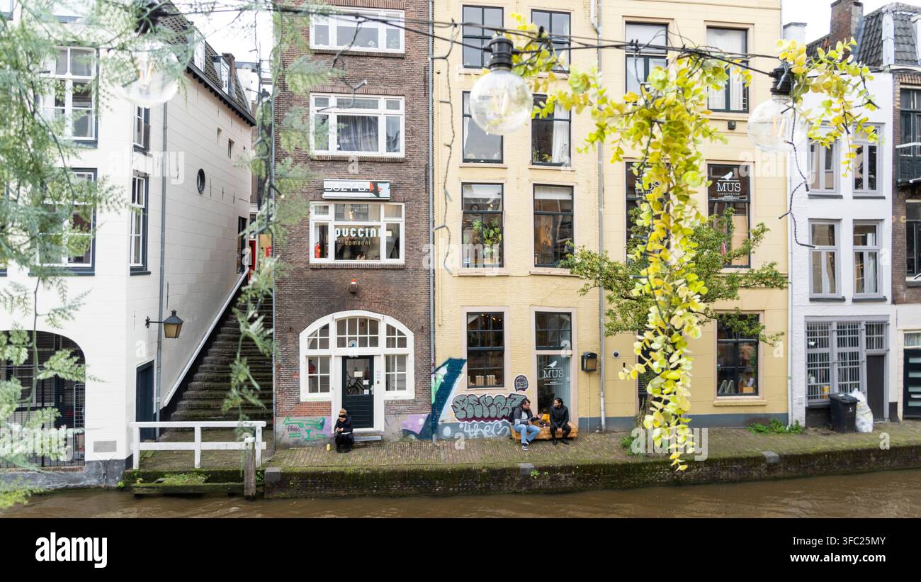 Cantine del molo del canale e facciate in mattoni tradizionali con persone sedute all'aperto lungo l'Oudegracht a Utrecht, Paesi Bassi Foto Stock