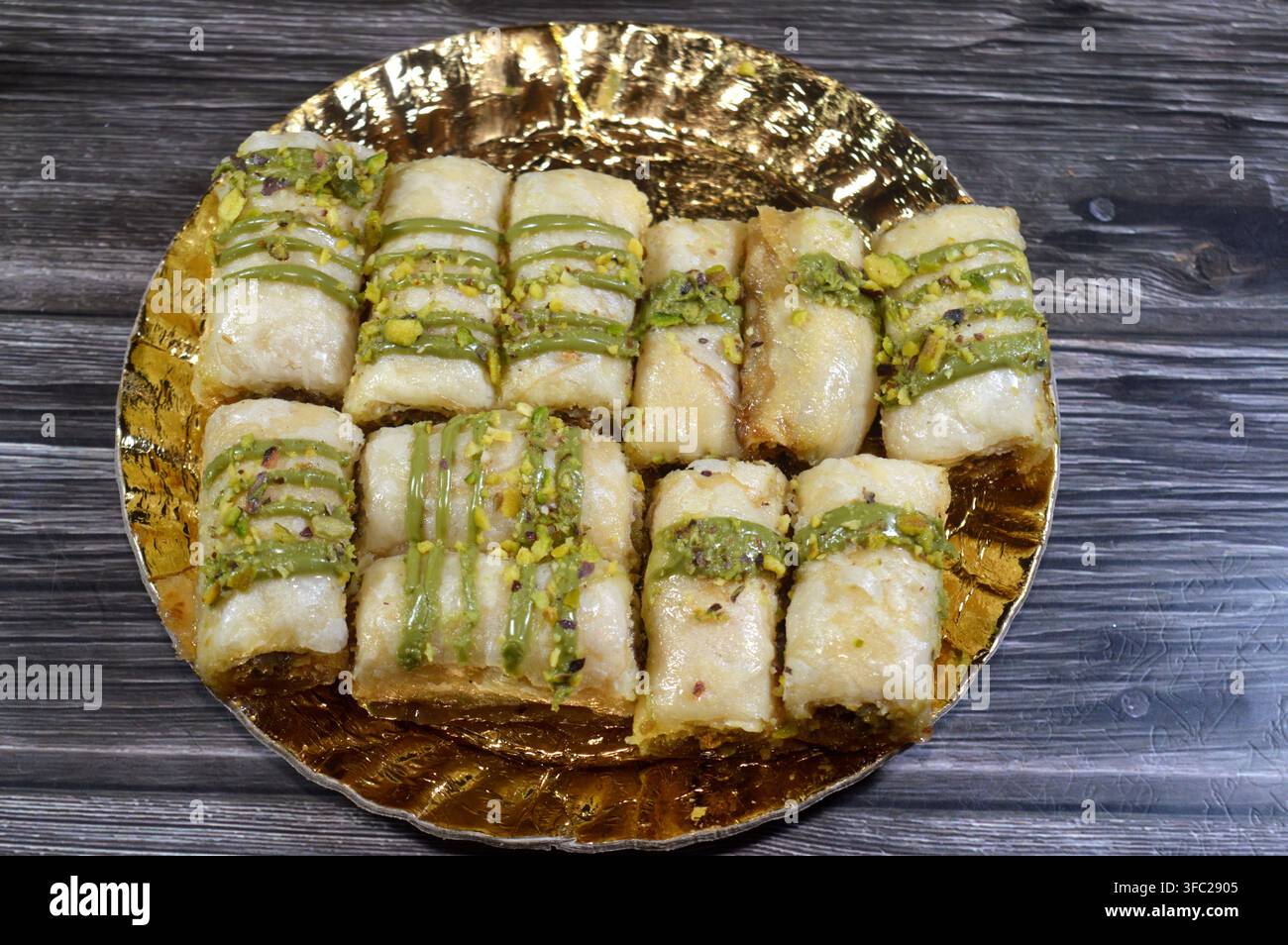 Rotoli di baklava alle pistacchi, gusci di pasta sfoglia multistrato ripieni di konafa e noci, bagnati con una salsa verde alle pistacchi, un popolare piatto del Medio Oriente Foto Stock