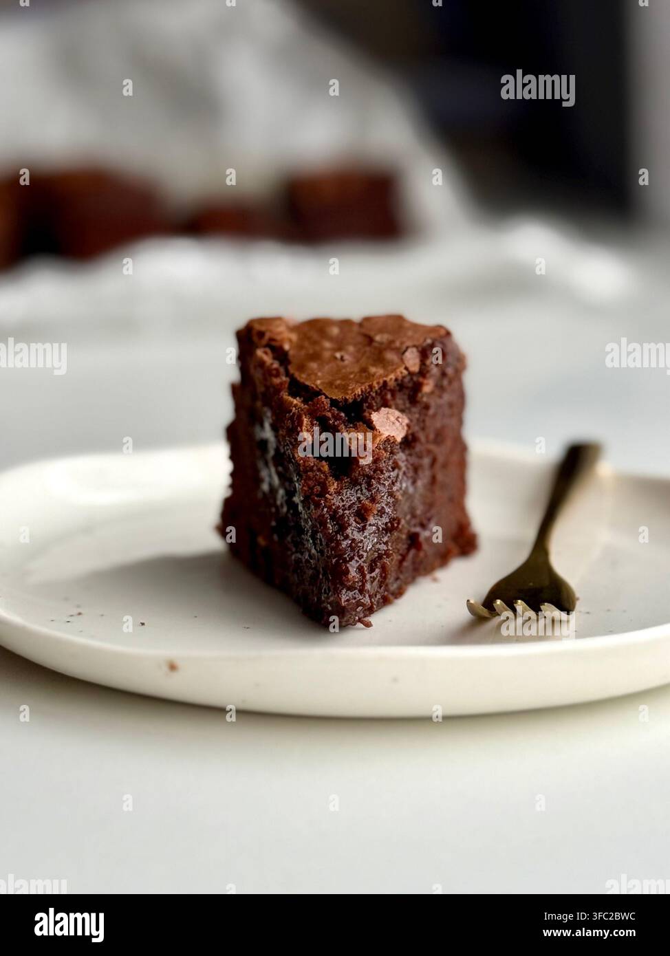 Prima vista di una fetta di torta al cioccolato umida servita su un piatto bianco con forchetta Foto Stock