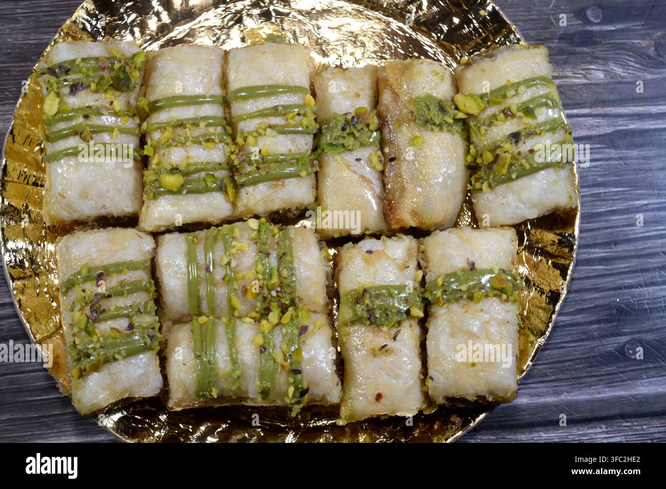 Rotoli di baklava alle pistacchi, gusci di pasta sfoglia multistrato ripieni di konafa e noci, bagnati con una salsa verde alle pistacchi, un popolare piatto del Medio Oriente Foto Stock