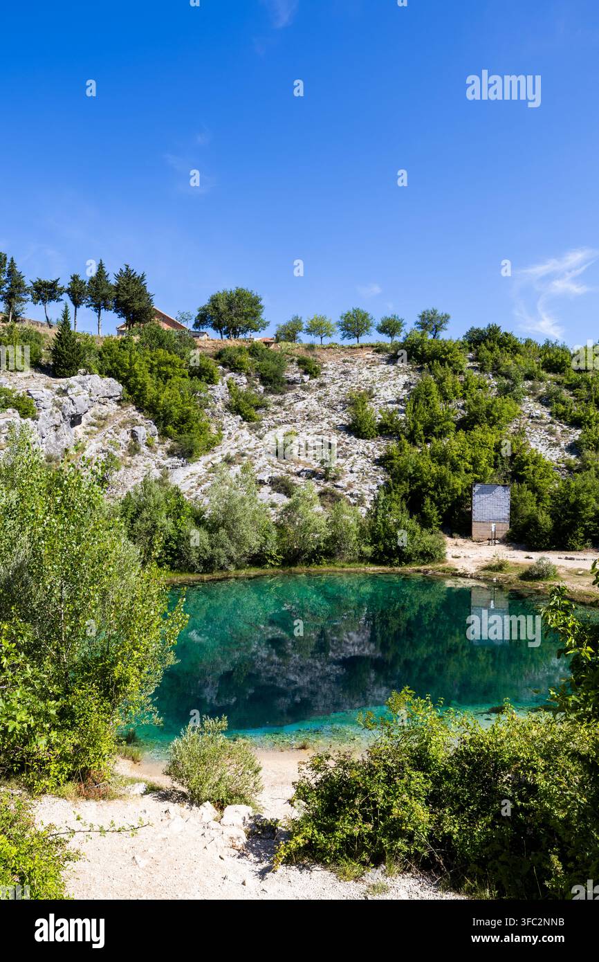 Acqua turchese profonda dell'occhio della sorgente del fiume Cetina sotto un cielo blu Foto Stock