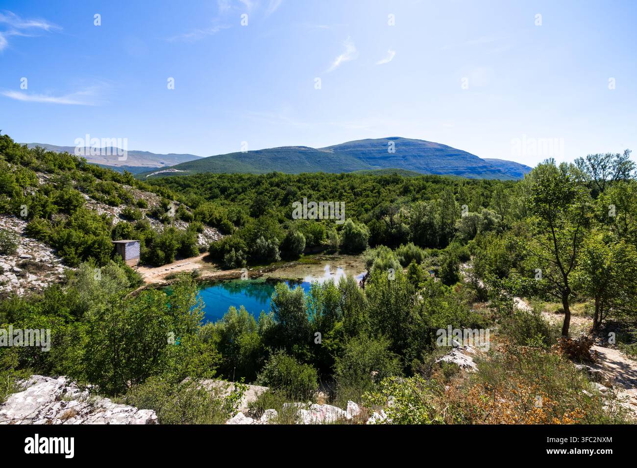 Acqua turchese profonda dell'occhio della sorgente del fiume Cetina sotto un cielo blu Foto Stock