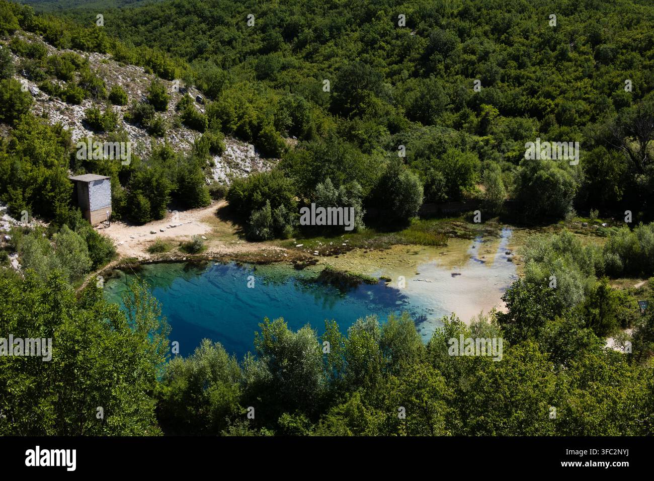 Acqua turchese profonda dell'occhio della sorgente del fiume Cetina sotto un cielo blu Foto Stock