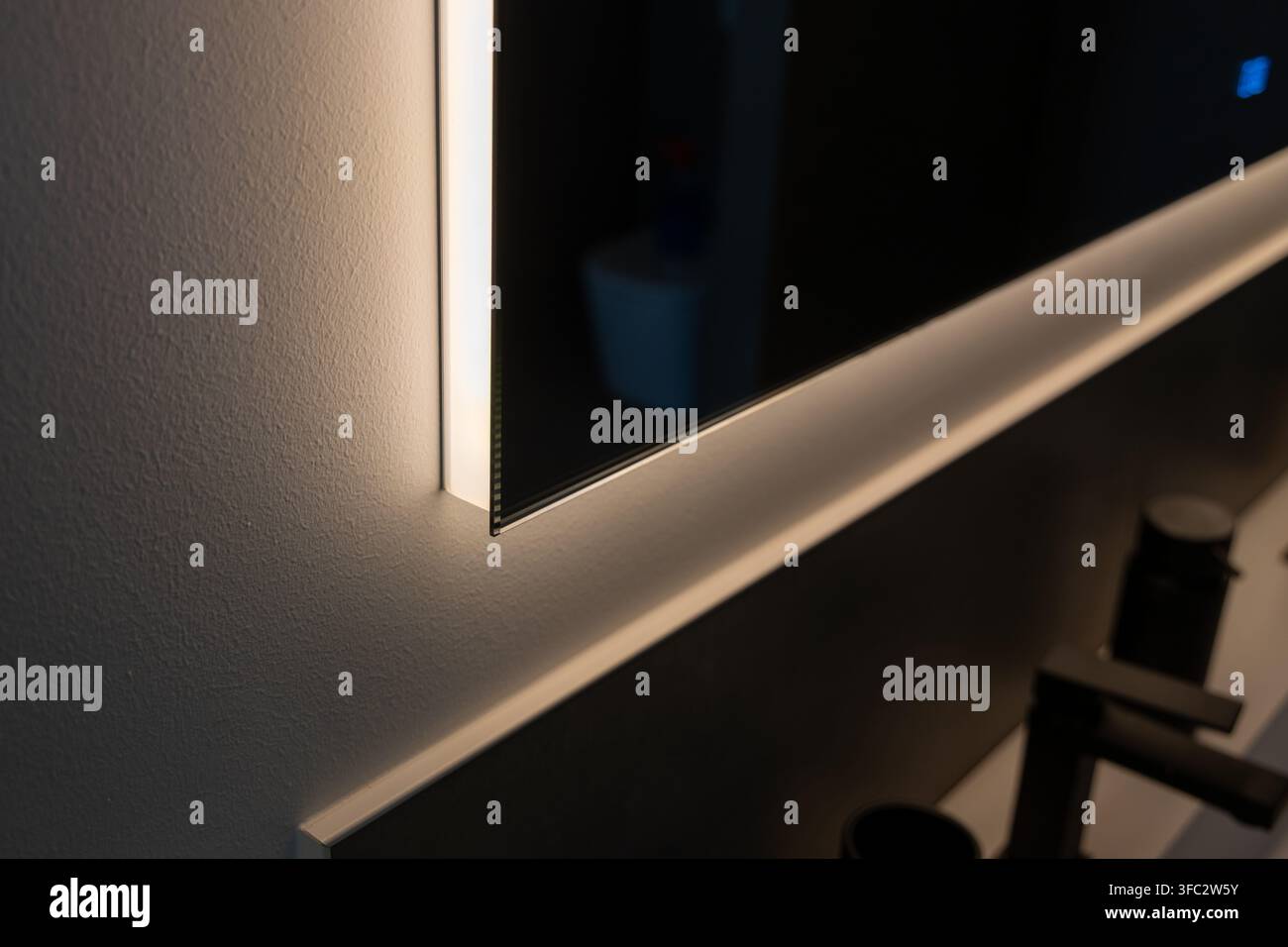 Un lavabo da bagno contemporaneo con specchio a illuminazione LED sottile e rubinetto nero minimalista, che crea un'atmosfera sofisticata Foto Stock