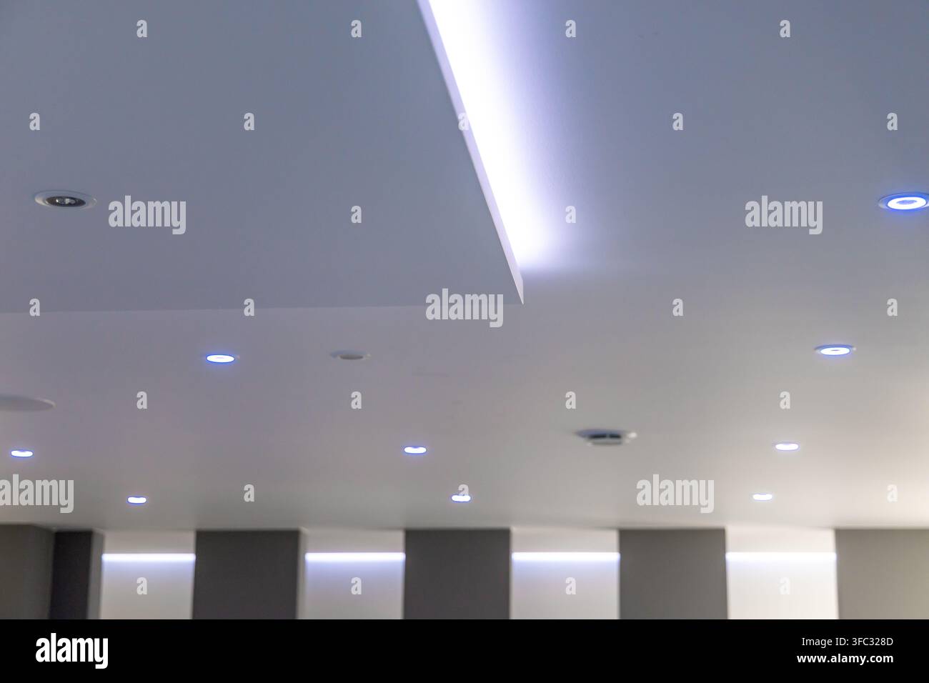 Un design contemporaneo per il soffitto degli interni che include più faretti incassati e illuminazione a striscia LED integrata per un'atmosfera sofisticata Foto Stock