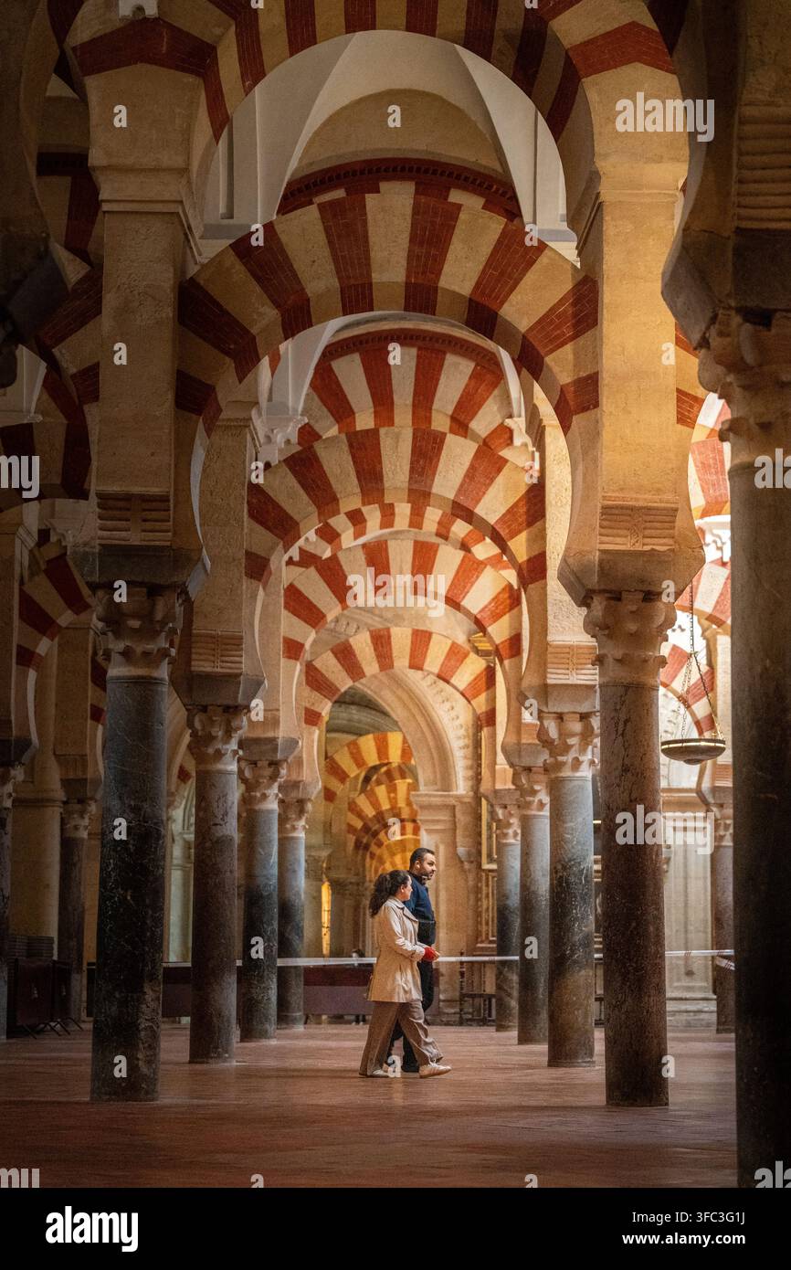 Due persone che camminano attraverso gli archi della Moschea-Cattedrale di Cordova Foto Stock