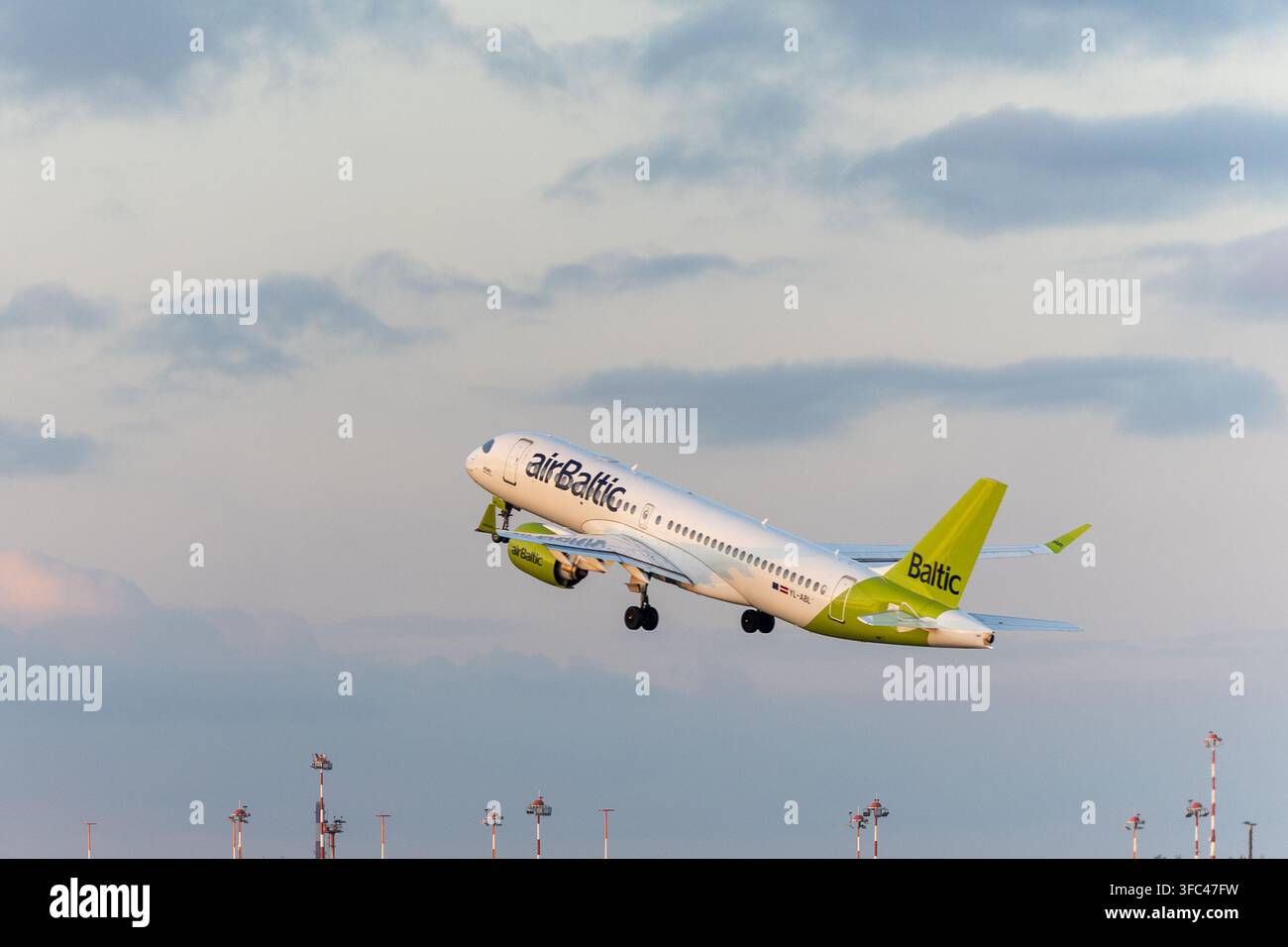 Riga, Lettonia - 25 agosto 2026: aereo Airbus A220 di airBaltic che decolla dall'aeroporto internazionale di Riga nella calda luce serale. Foto Stock