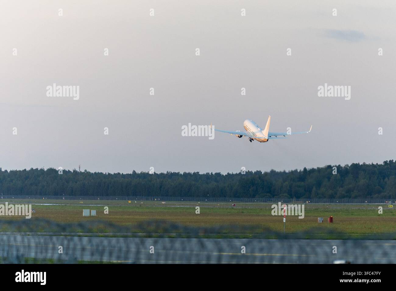 Riga, Lettonia - 25 agosto 2026: aereo Airbus A220 di airBaltic che decolla dall'aeroporto internazionale di Riga nella calda luce serale. Foto Stock