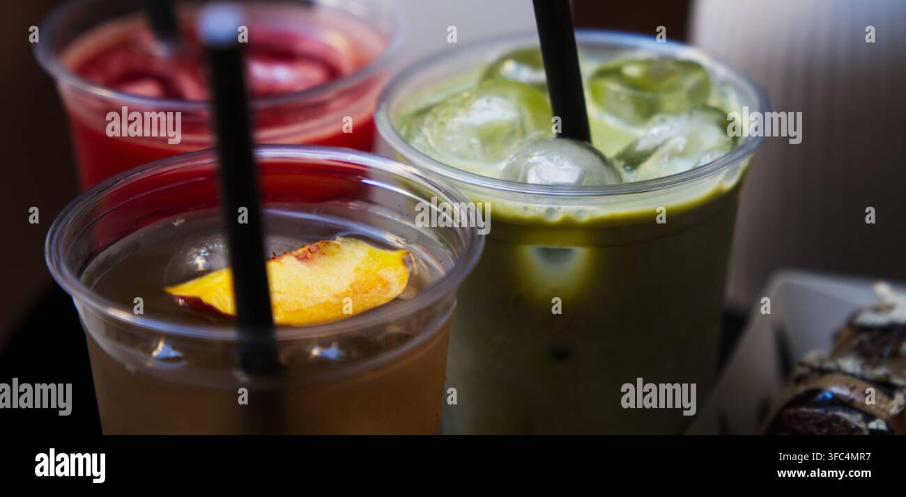 Prima piano di varie bevande fredde da asporto tra cui tè verde matcha ghiacciato, tè freddo alla pesca e succo di frutti di bosco. Foto Stock