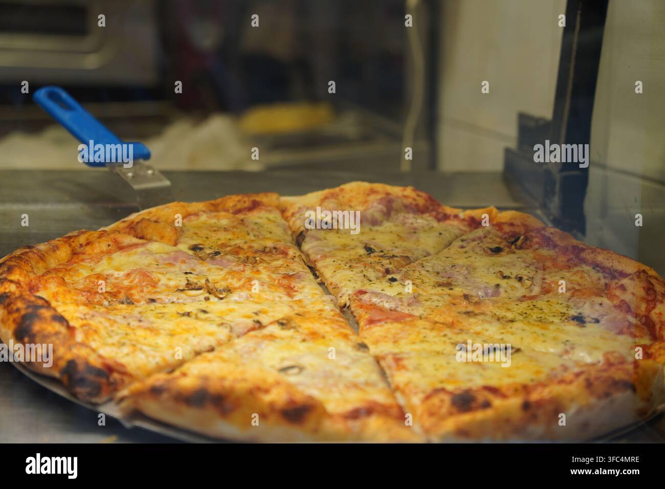 Pizza appena sfornata con formaggio fuso e condimenti tagliata a triangoli Foto Stock