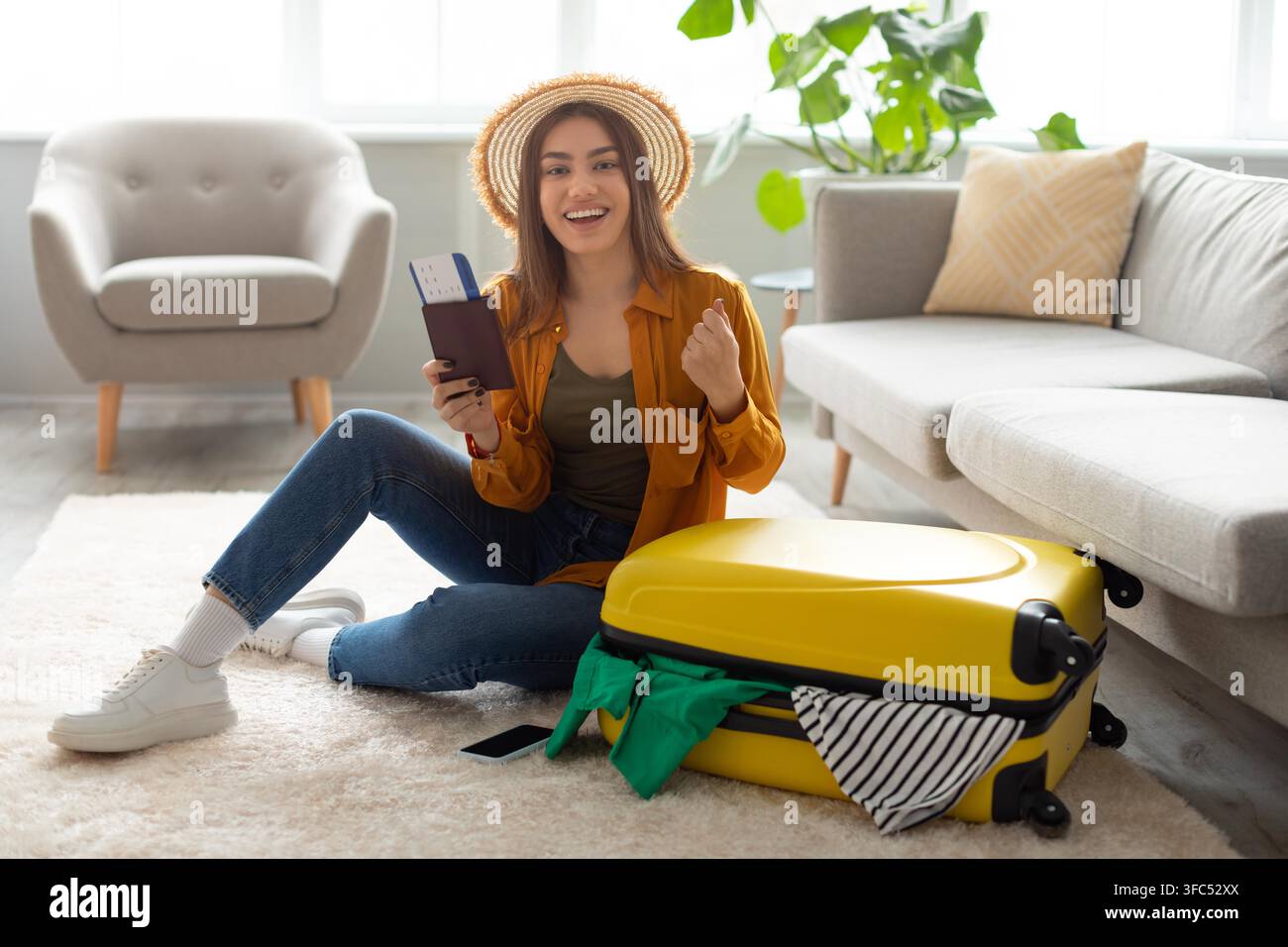 Giovane donna ispanica felice che prepara la valigia per un viaggio con bagaglio giallo a casa, preparazione del viaggio Foto Stock