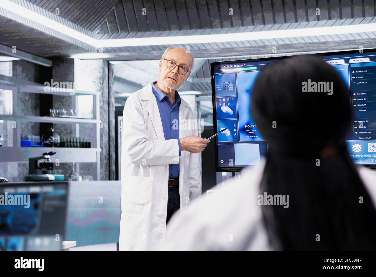 Biologo senior di laboratorio che informa i colleghi sui nuovi protocolli sperimentali. Uomo anziano in laboratorio che utilizza un display digitale per spiegare dati biologici complessi ai membri del personale Foto Stock