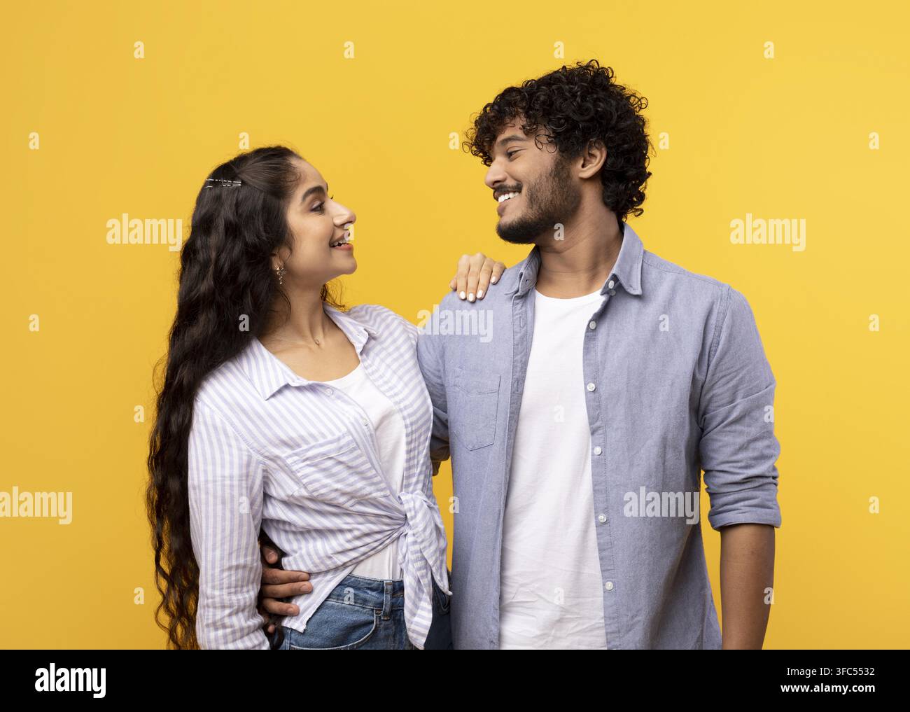 Coppia che sorride e si abbraccia su sfondo giallo, concetto di relazione felice Foto Stock