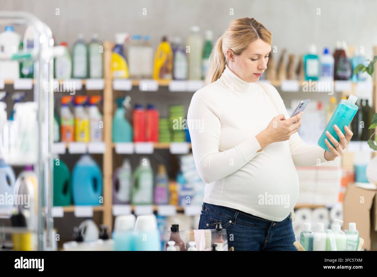 Donna incinta che scansiona il codice QR sullo shampoo per il pagamento online Foto Stock