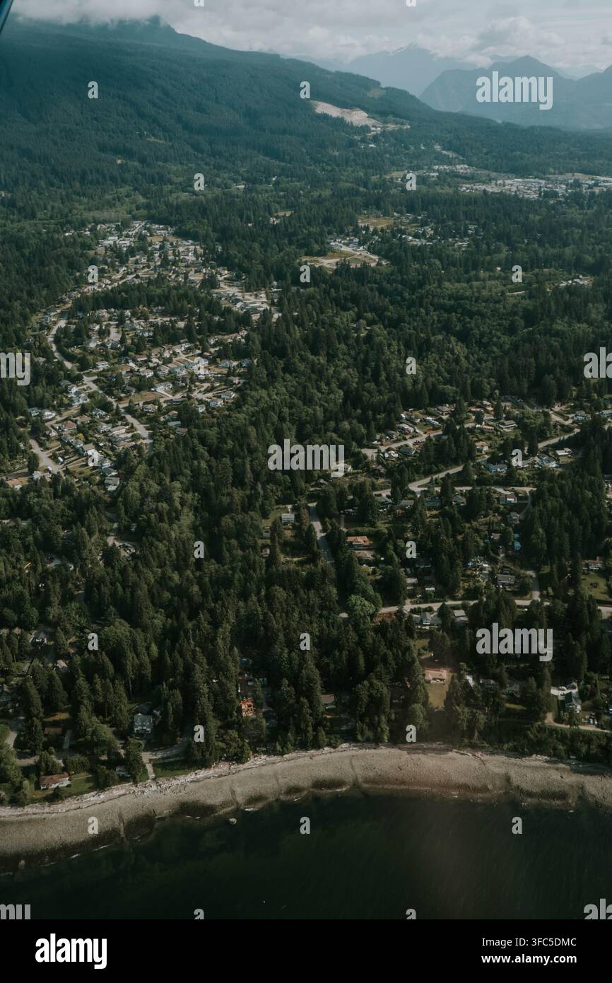 Vista elevata di una comunità costiera boschiva circondata da montagne nella British Columbia, Canada Foto Stock