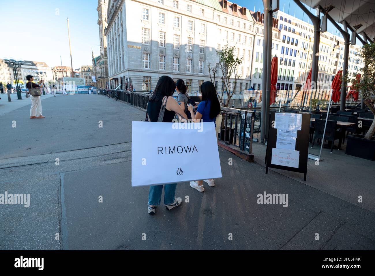 Acquistiatori con una grande borsa della spesa Rimowa su una strada nel centro di Amburgo, Germania. Foto Stock