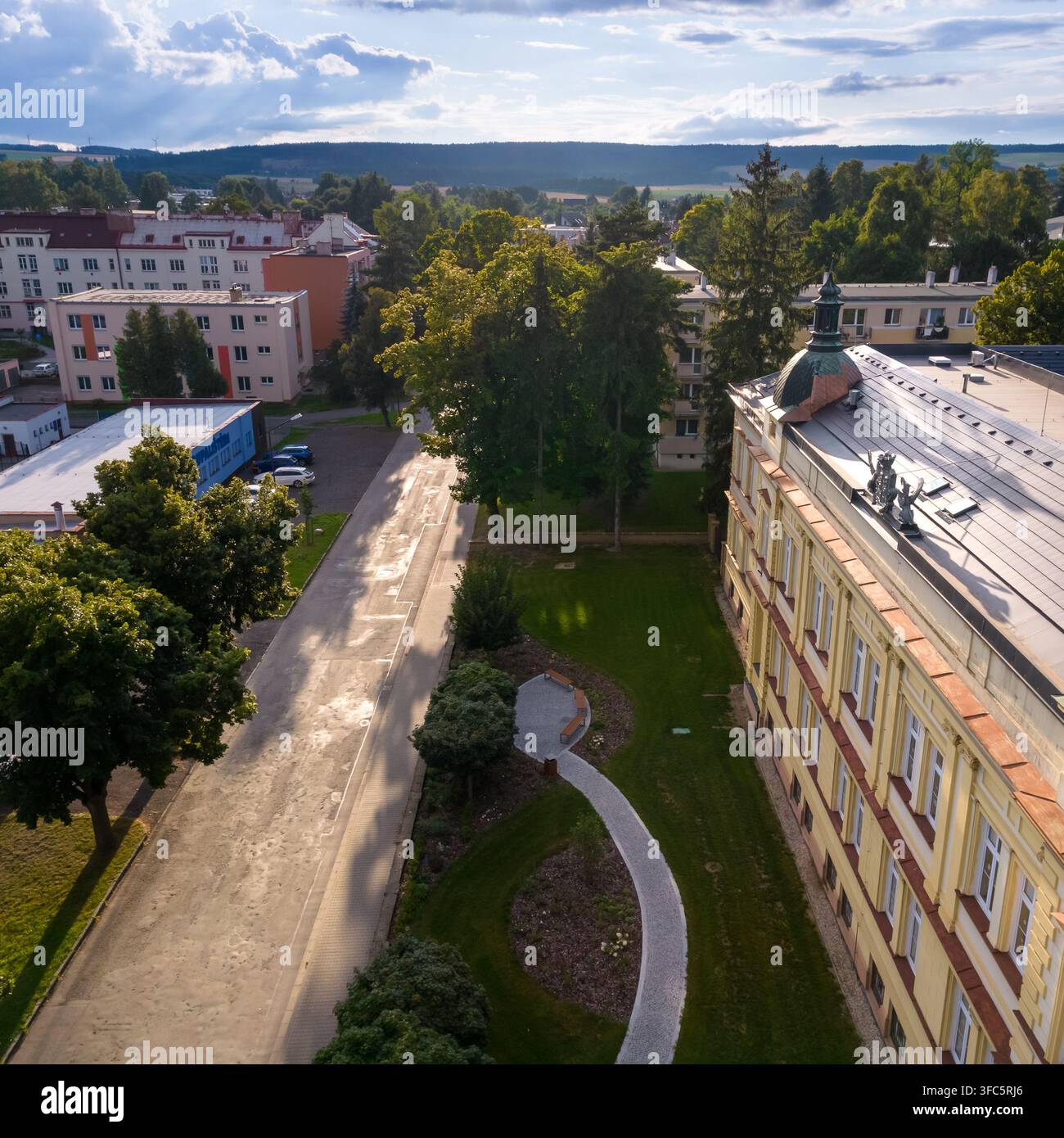 Vista aerea di un edificio storico giallo con un tetto a cupola, un parco verde con un sentiero di pietra sinuoso e edifici residenziali circostanti, Repubblica Ceca Foto Stock