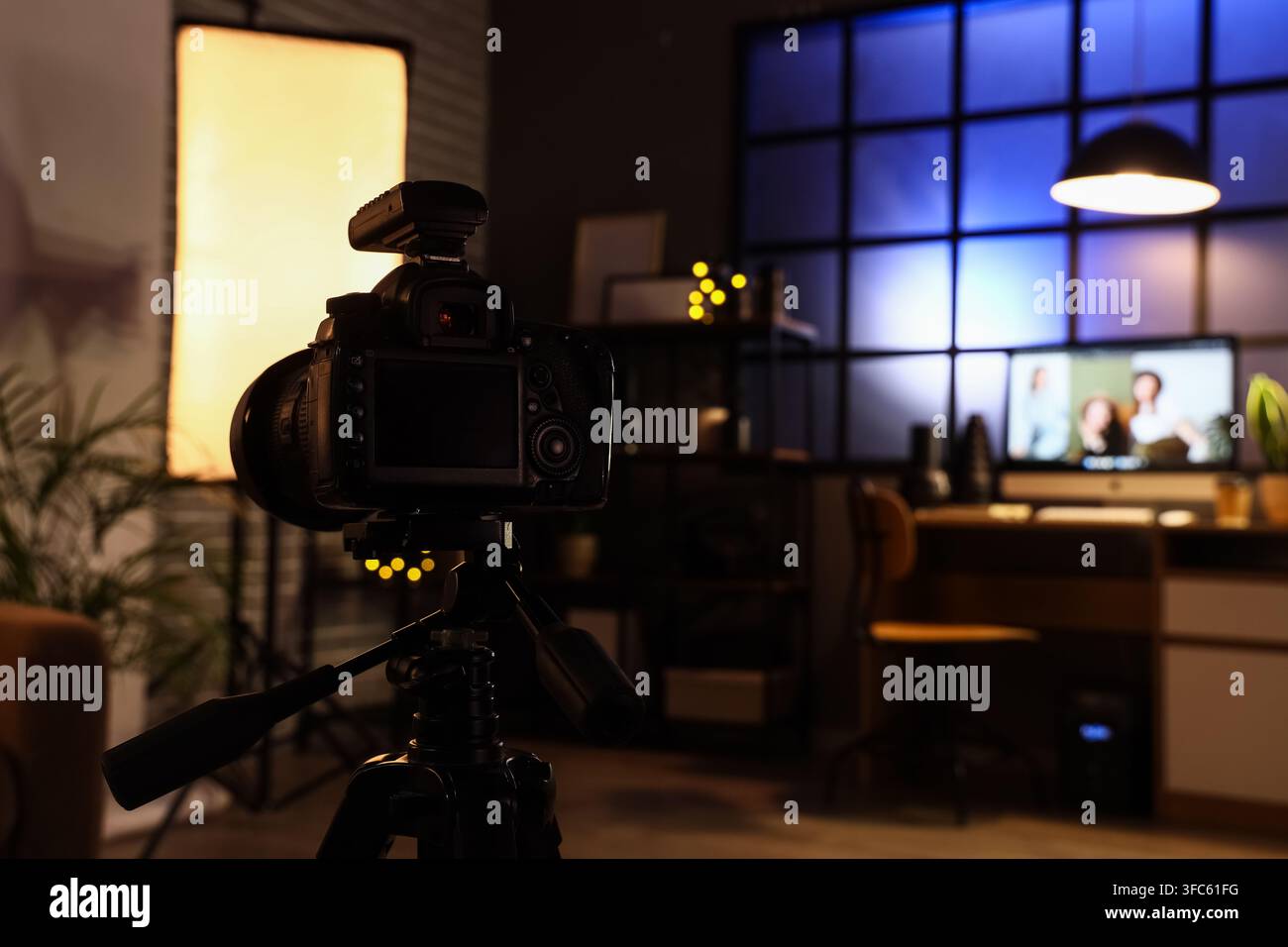 Produzione video e creazione di contenuti, fotocamera su treppiede nello studio di casa con softbox e chiamata video al computer Foto Stock