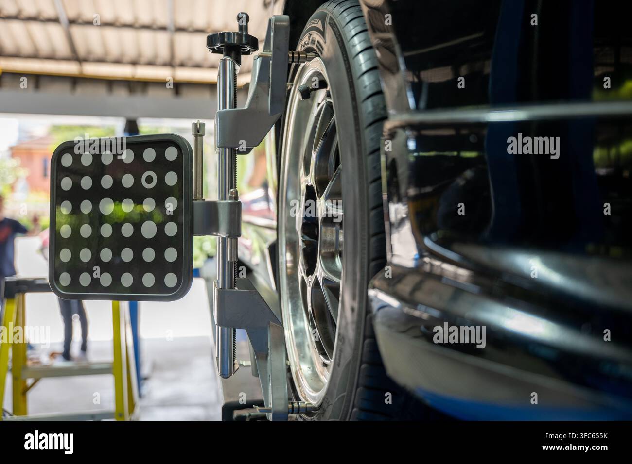 Primo piano dell'allineamento delle ruote di un'auto in un centro di riparazione automobilistica. Servizio di manutenzione veicoli in un'officina automobilistica con attrezzature meccaniche per l'equilibrio dei pneumatici Foto Stock