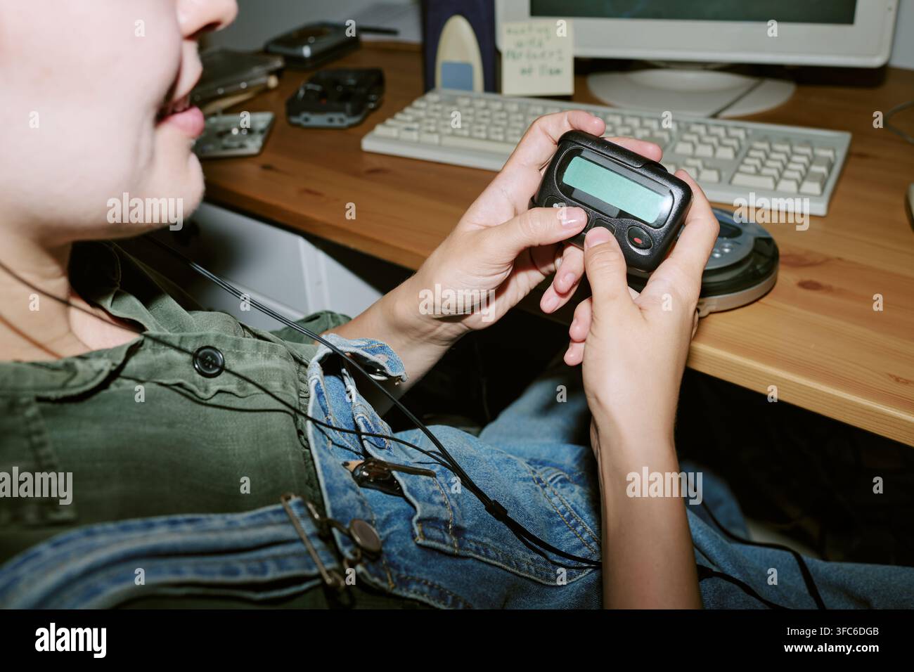 Donna che tiene un pager vintage a una scrivania da ufficio retrò Foto Stock